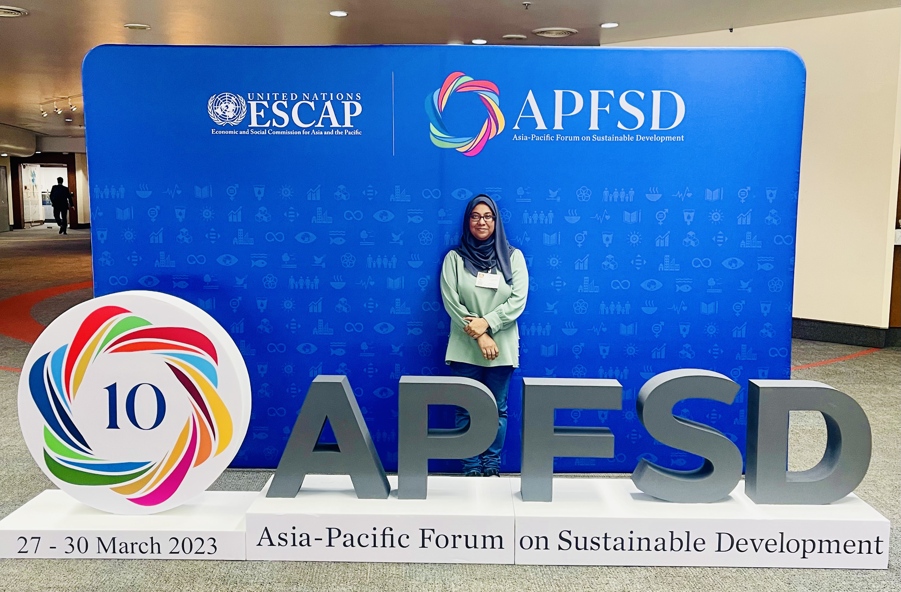 IFLA representative Fathimath Nashfa standing behind a 10th Asia-Pacific Forum on Sustainable Development logo, with a blue background